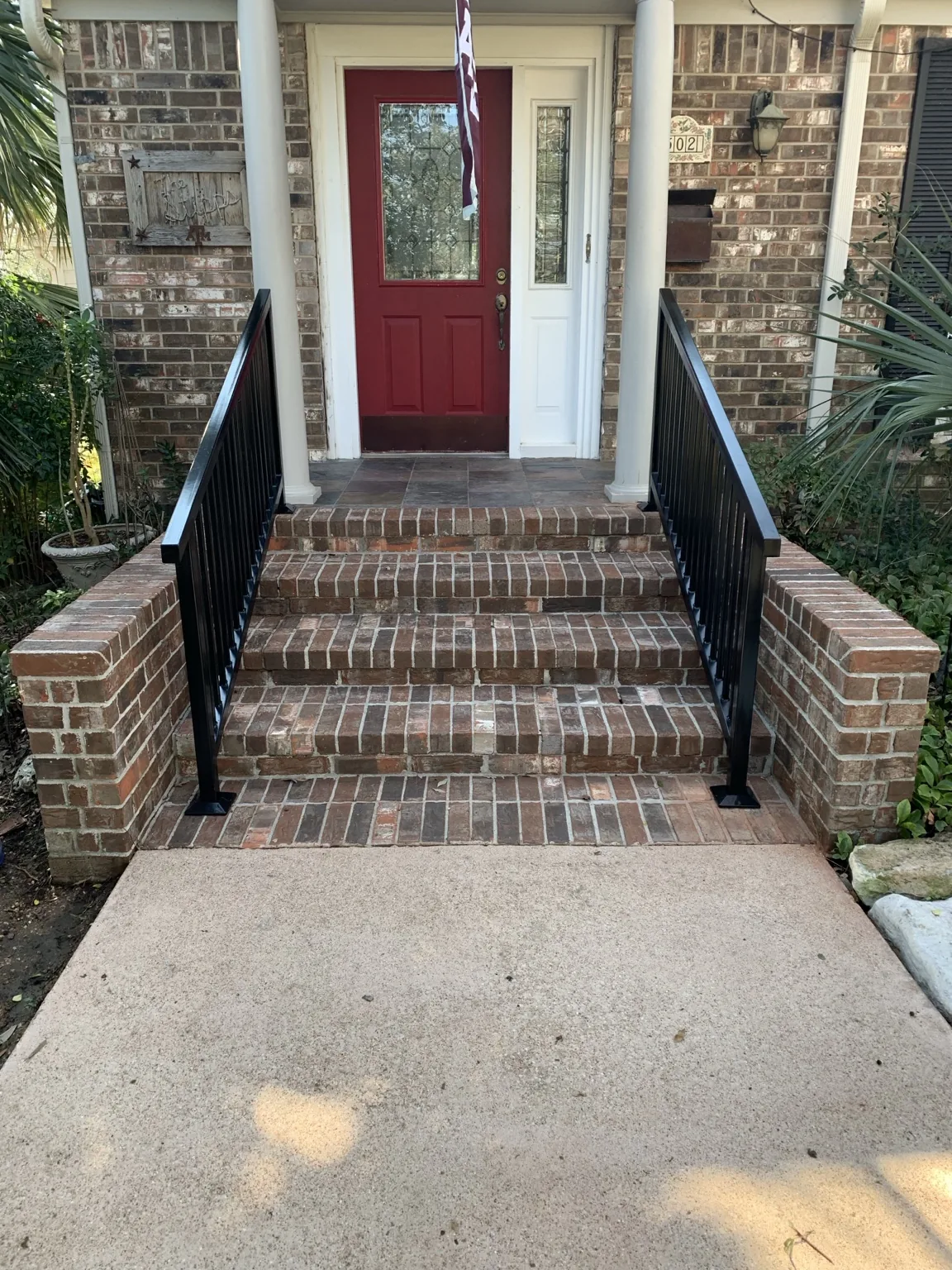 Pair of black steel handrails installed along brick front steps