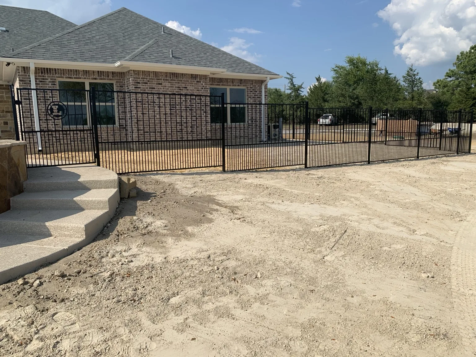 Black metal picket fence and matching gate installed around a residential property
